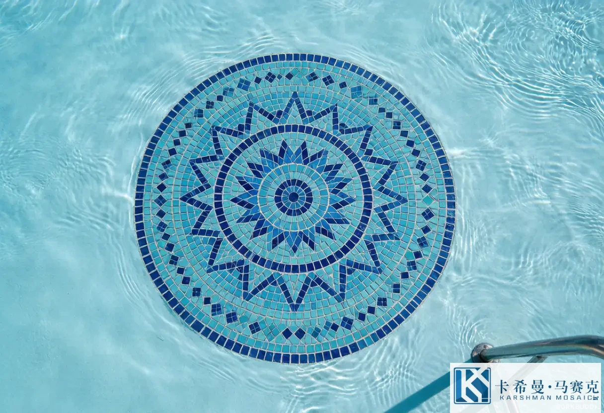 Aerial view of a circular mosaic medallion centered on a pool floor in blue and turquoise tiles