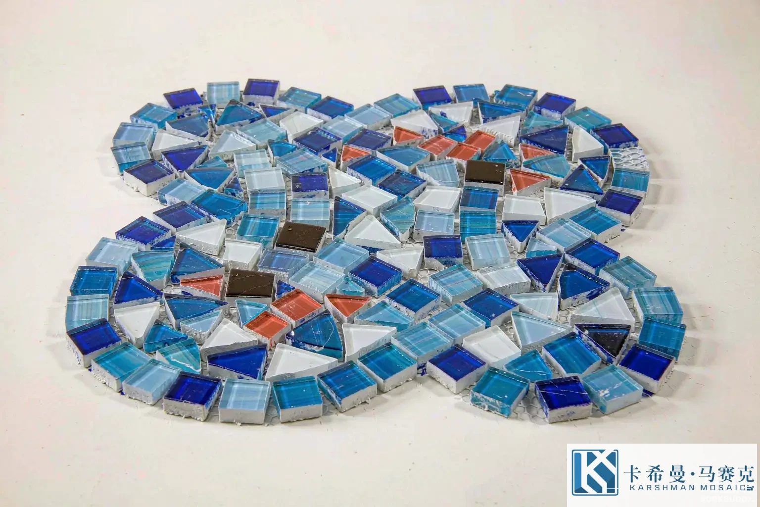Close up of a glass mosaic tile sheet in Mediterranean blue white and terracotta tones on a sample board