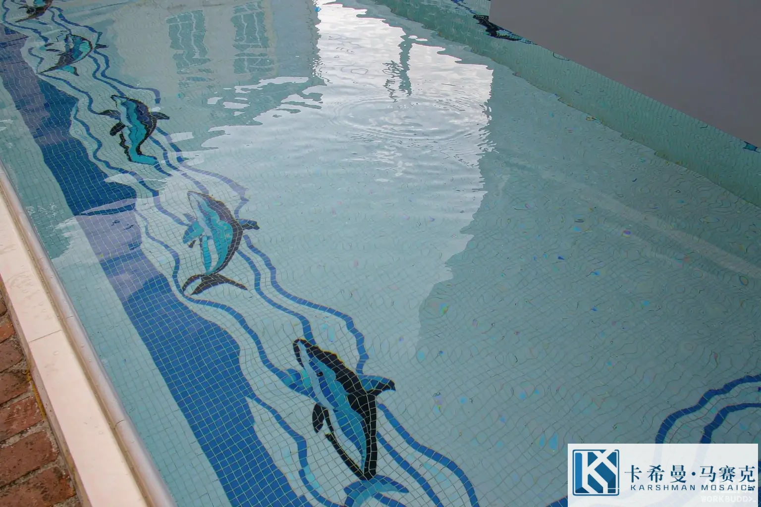 Underwater view of a swimming pool lined with a classic blue and white European glass mosaic of leaping dolphins and a wave band