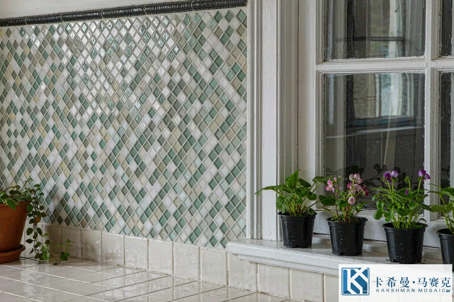 Close view of a glass mosaic backsplash in white and sea-green tesserae beside a kitchen window with herb pots
