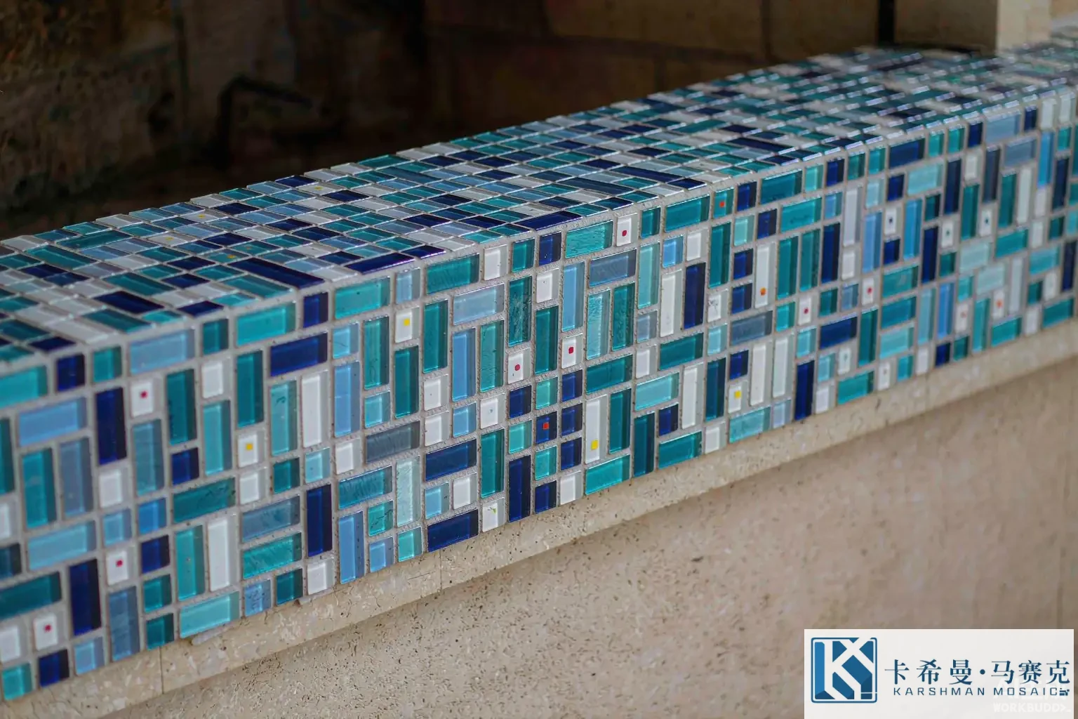 Close detail of a small glass mosaic accent border along a fireplace surround in glossy blue and white tiles